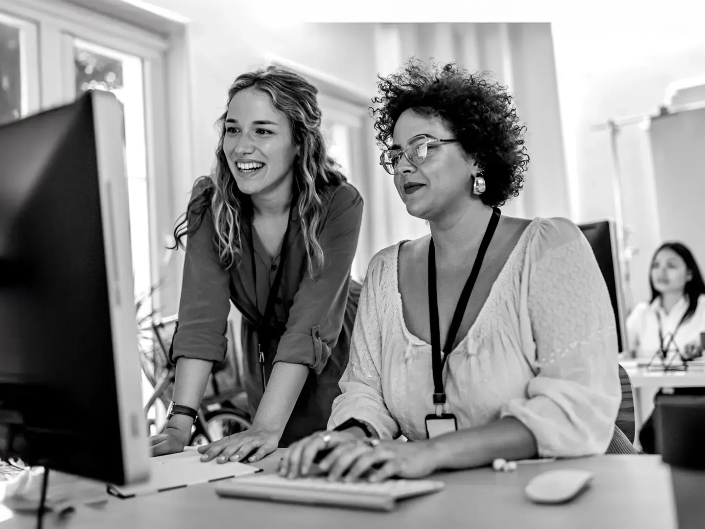 A trainer collaborating and teaching a coworker how to use all the incredible office technology.